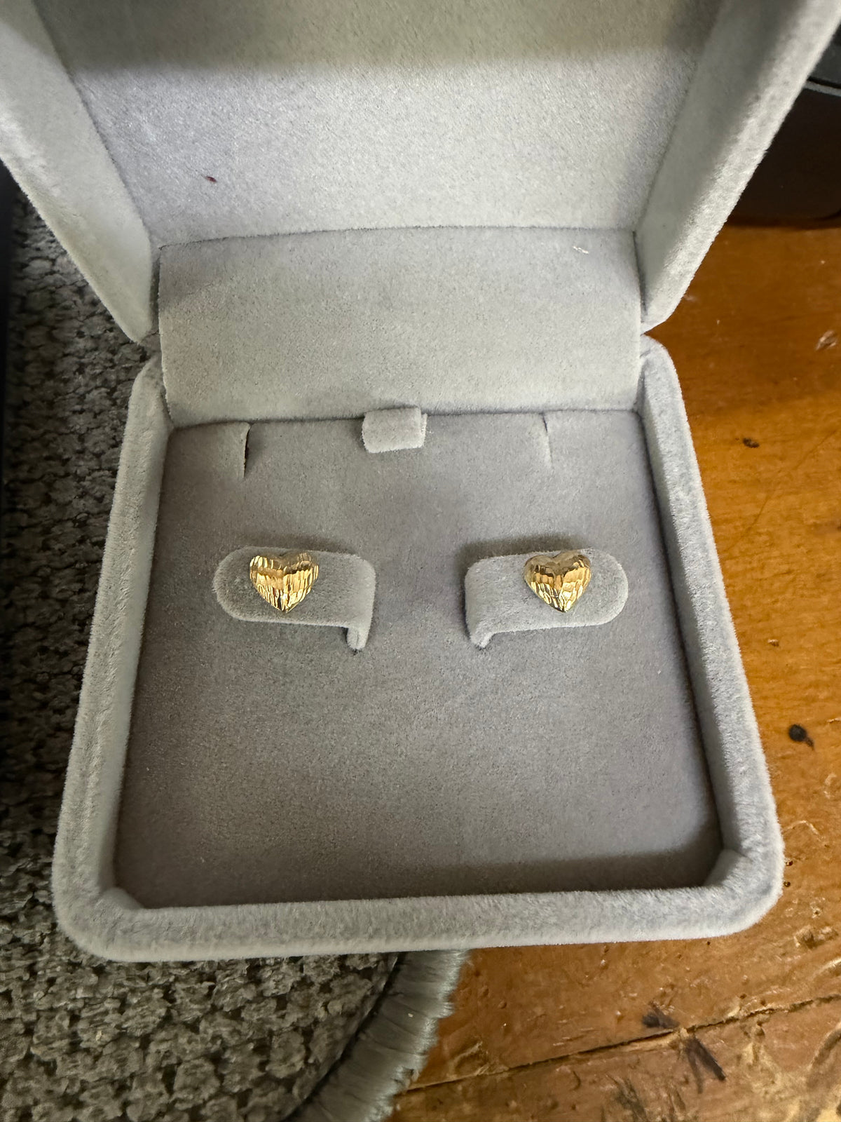 Pair of 14K yellow gold heart earrings displayed in a jewelry box