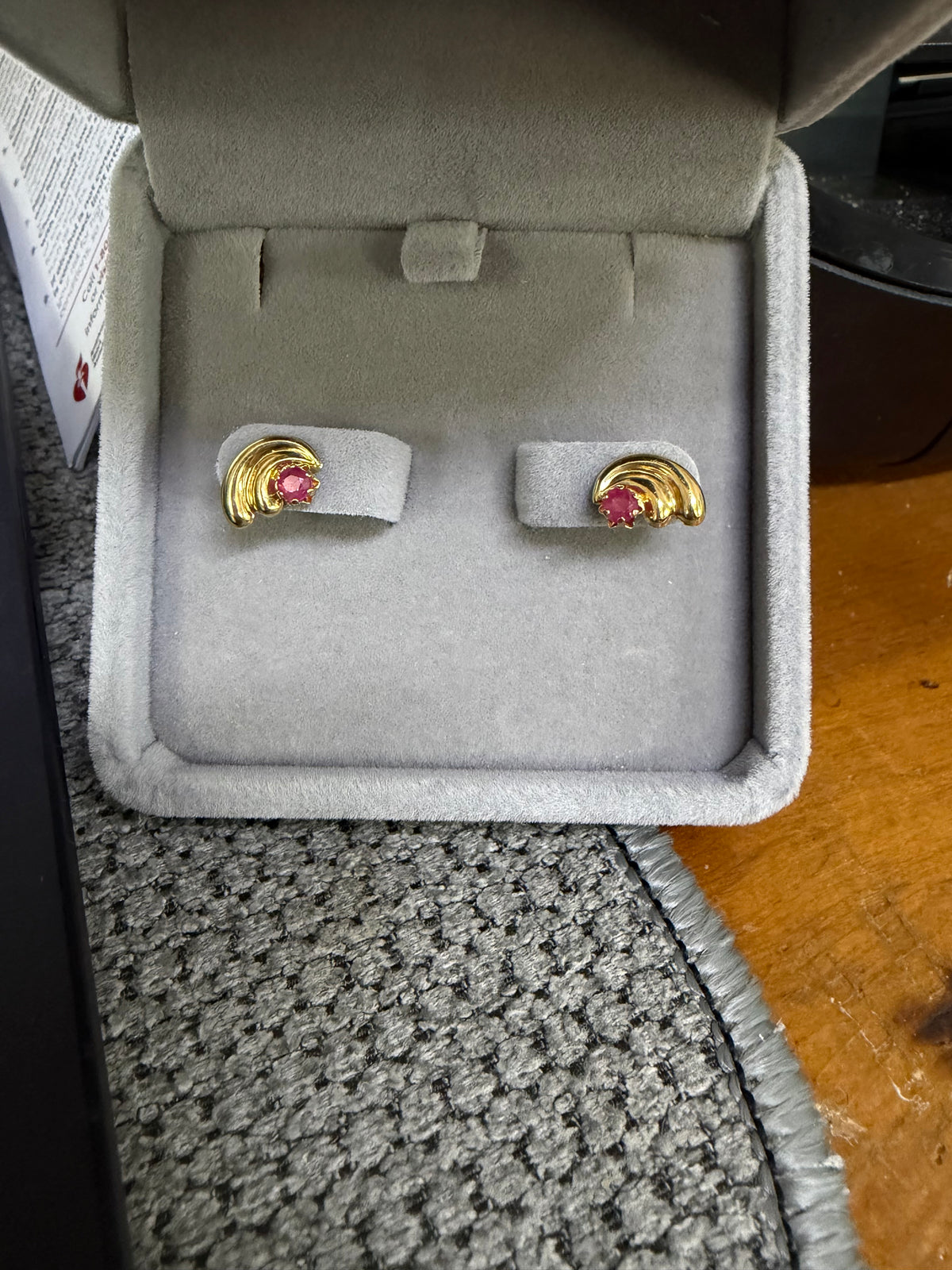 Pair of 14K yellow gold 0.15ctw natural ruby earrings displayed in a jewelry box