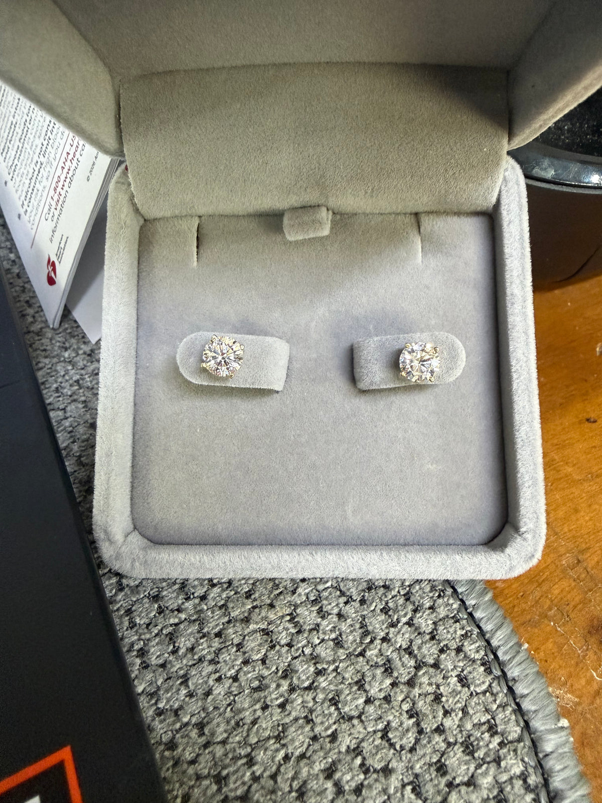 Pair of 14K yellow gold 1.50ctw lab diamond earrings displayed in a jewelry box