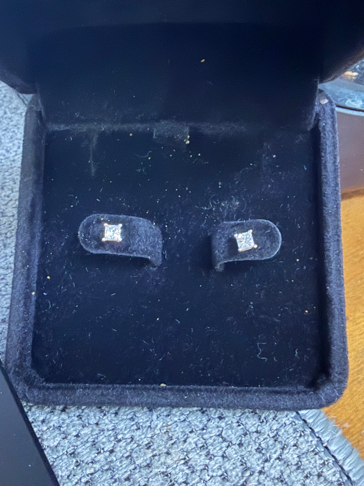 Pair of 14K white gold 0.50ctw natural princess-cut diamond earrings displayed in a jewelry box