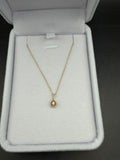 Yellow gold teardrop diamond pendant shown with a chain in a light-colored jewelry box